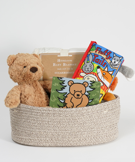 new baby gift basket featuring teddy bear, blanket, and baby books.