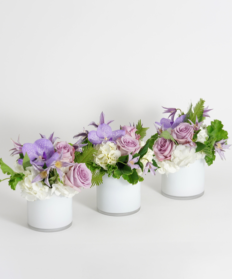 lavender roses, orchids, and clematis designed in white glass vases for breakaway style centerpiece