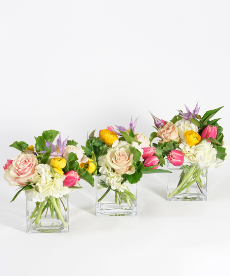 trio style centerpiece of pastel spring blooms including tulips, roses, and hyacinth in clear glass vases