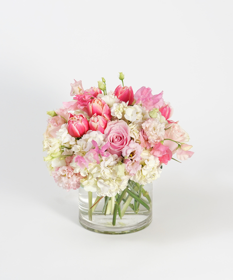 low and lush floral arrangement of peach roses, pink lisianthus, and white hydrangea