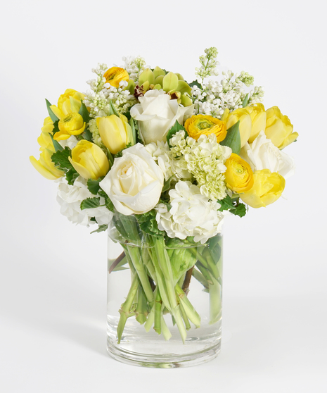 gardeny spring floral design of yellow and white blooms accented with seasonal greens